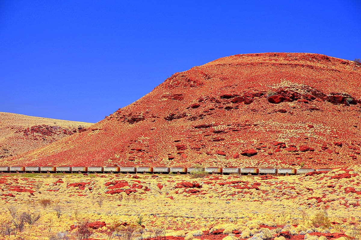 An iron ore train crosses the rugged Pilbara terrain.